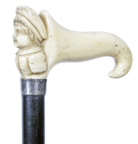 147. Ivory Dress Cane-Ca. 1885-An ivory handle with a: 147. Ivory Dress Cane-Ca. 1885-An ivory handle with a young boy with a tasseled hat, silver metal collar, ebony shaft and a horn ferrule-H. 3” x 1 ½”, O.L. 36 ½”