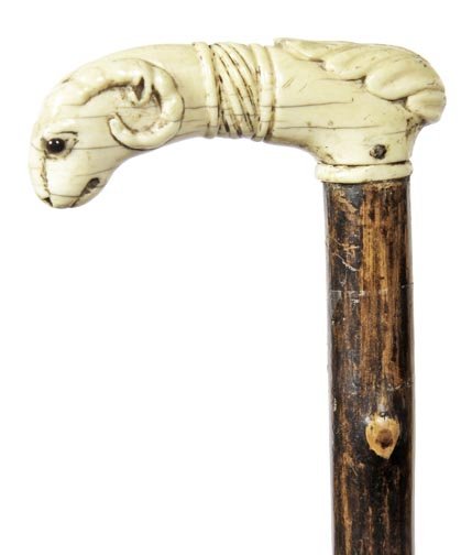 152. Ram’s Head Ivory Cane-Ca. 1850-An early ivory: 152. Ram’s Head Ivory Cane-Ca. 1850-An early ivory handle carved in the shape of a ram with glass eyes, early twig spur shaft and no ferrule-H. 3 ¼” x 1”, O.L. 33 ¼”