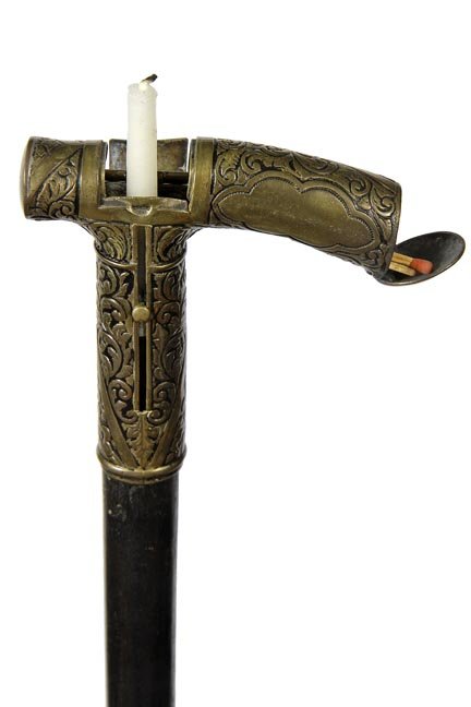 175. Vesta Match Safe Cane-Dated 1887-A push-up candle: 175. Vesta Match Safe Cane-Dated 1887-A push-up candle stick with a match holder on a spring loaded end cap, ornate brass handle which is patented, hardwood shaft and a metal ferrule-H. 4” x 3 ¾”