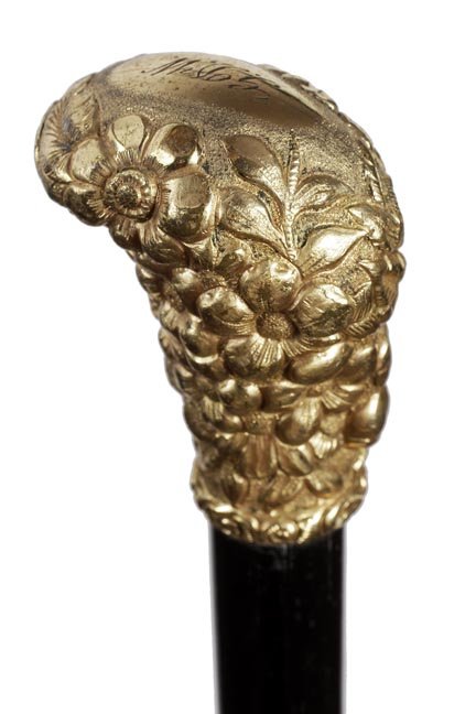 164. Gold Dress Cane- Ca. 1895- Gold-filled ornate: 164. Gold Dress Cane- Ca. 1895- Gold-filled ornate handle with various flowers including roses, ebony shaft and a metal ferrule. H. 1 ¾” x 2 ¼”, O.L.-35”