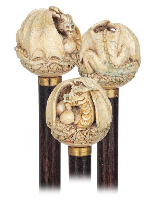 64. Ivory Dragon Cane-Ca. 1900-Ivory ball handle carved: 64. Ivory Dragon Cane-Ca. 1900-Ivory ball handle carved with a dragon breeding two large eggs, well-streaked rosewood shaft with a plain, gilt metal collar and a stag horn ferrule. The legendary creat