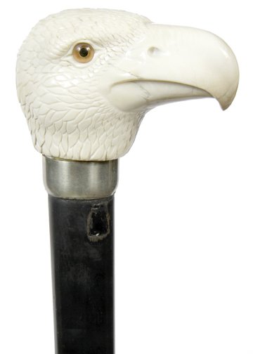 36. Ivory Eagle Cane- Pre-Ban-A large bald eagle head: 36. Ivory Eagle Cane- Pre-Ban-A large bald eagle head with two color glass eyes, detailed feather work, silver metal work, 1” ebony shaft and a horn ferrule-H. 4” x 2” x 2 ¼”, O.L. 36”