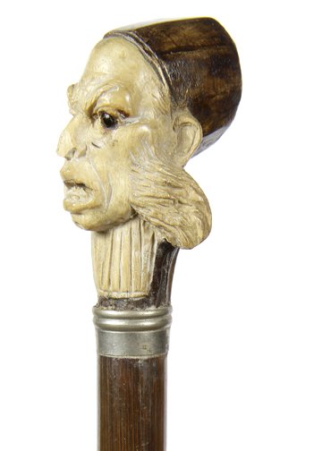 242.”One Eyed Pirate” Cane- Ca.1860- A carved ivory and: 242.”One Eyed Pirate” Cane- Ca.1860- A carved ivory and wood handle with an evil pirate with one glass eye, white metal collar hard wood shaft and a metal ferrule, H.1 ½” x 2”, O.L.35 ½ “