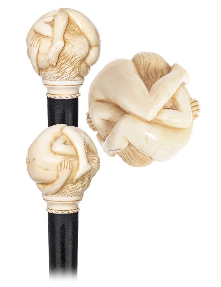 13. Ivory Erotic Cane-Ca. 1890-Ivory ball carved with: 13. Ivory Erotic Cane-Ca. 1890-Ivory ball carved with two women engaged in an erotic embrace, short turned ivory stem with rope pattern collar, ebony shaft and a stag horn ferrule. French cane and end