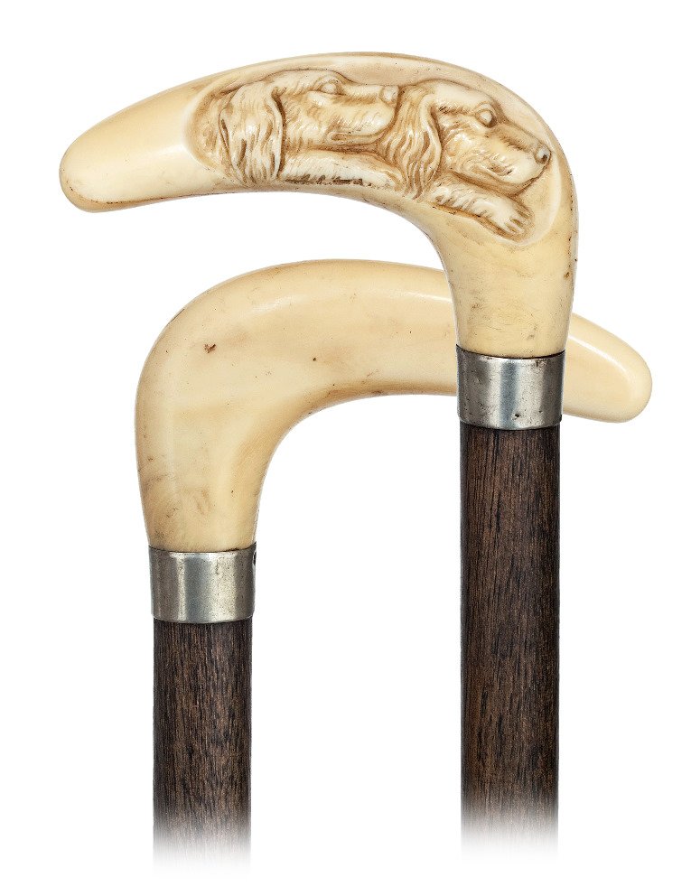 111. Ivory Dogs Cane-Ca. 1890-L-Shaped hippopotamus: 111. Ivory Dogs Cane-Ca. 1890-L-Shaped hippopotamus ivory handle with rounded edges carved with two dog heads, fruitwood shaft with a white metal collar and a brass ferrule. -H. 3 ¾” x 2, O.L. 35 �