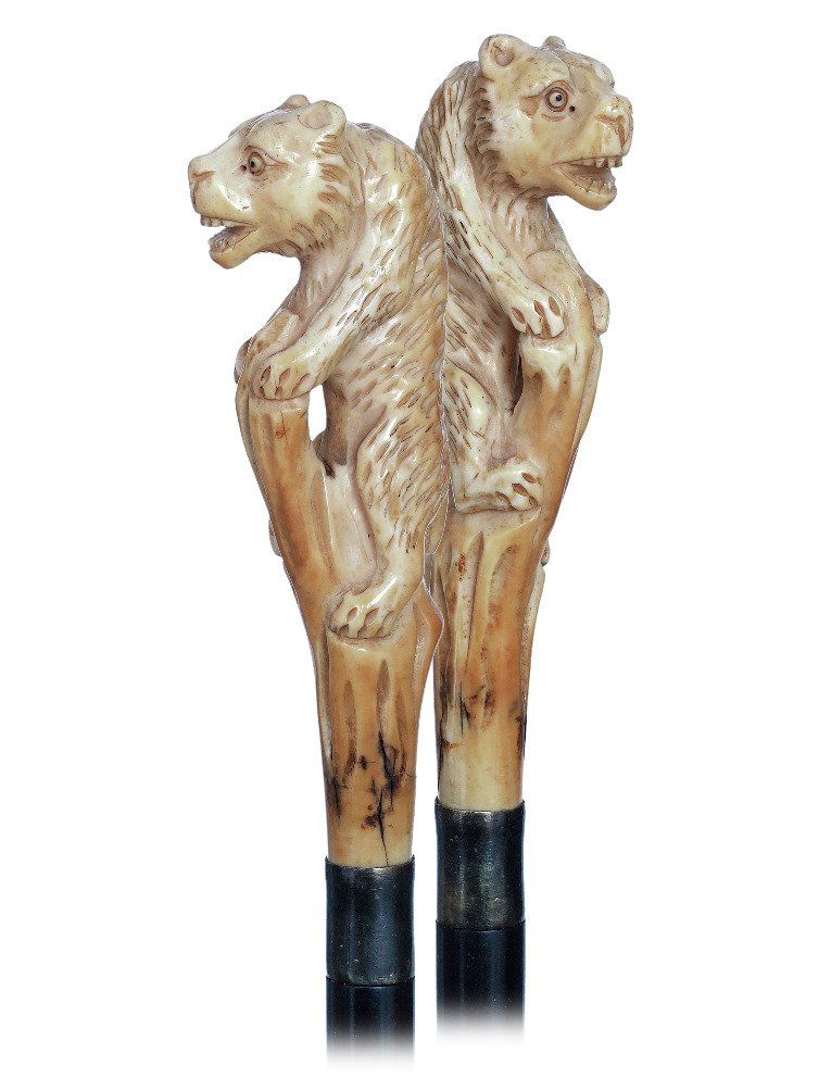 147. Figural Ivory Day Cane-Ca. 1900-Pistol shaped: 147. Figural Ivory Day Cane-Ca. 1900-Pistol shaped ivory handle carved with an upright bear leaning on a dried tree trunk, metal collar, ebony shaft and a stag horn ferrule. -H. 4 ¾” x 1 ¾”, O.L