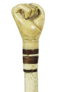 14. Nautical Fist Whalebone Cane-Ca. 1850-A whale’s: 14. Nautical Fist Whalebone Cane-Ca. 1850-A whale’s tooth handle carved in the form of a clinched fist, the owner’s name which is unreadable to our eye is on the wrist of the fist, exotic wood