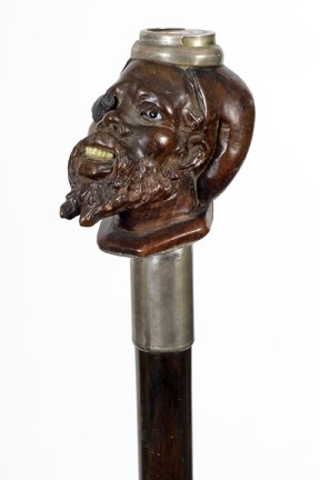 75. Nubian Change Purse Cane-Ca. 1880-A carved Nubian: 75. Nubian Change Purse Cane-Ca. 1880-A carved Nubian with one glass eyes and a patch over the other with carved teeth, spring loaded coin purse atop, silver metal collar, exotic wood shaft and a meta