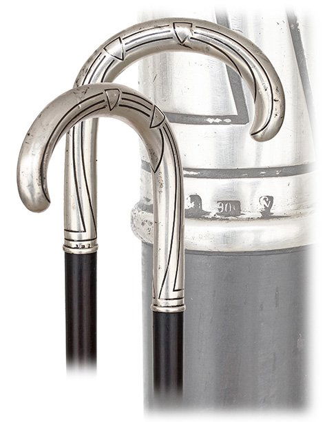 78. Silver Day Cane-Ca. 1910-Well-proportioned silver: 78. Silver Day Cane-Ca. 1910-Well-proportioned silver crook handle chased with a bold linear design in the taste of the Art Deco, ebony shaft and a horn ferrule. The German origin is authenticated wit