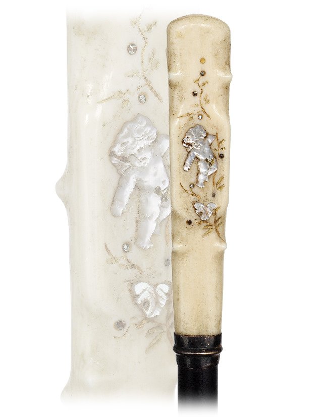 150. Ivory and Mother of Pearl Cane-Ca. 1900-Straight: 150. Ivory and Mother of Pearl Cane-Ca. 1900-Straight ivory handle fashioned in a flattened shape with faux sprig and applied with a cavorting Cupid among engraved floral. Ebony shaft with a metal col