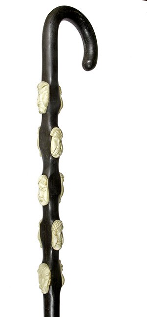 29. Johnny Winter Mask Cane- 20th Century- A one piece: 29. Johnny Winter Mask Cane- 20th Century- A one piece crutch handle ebony cane with ten various carved bone faced attached, all of the faces are in high relief and a horn ferrule. O.L.- 36” $250-