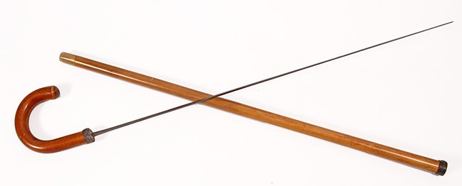 44. Sword Cane- Ca. 1900- A crook handle malacca sword: 44. Sword Cane- Ca. 1900- A crook handle malacca sword cane, woven leather collars, horn ferrule, 27” two-sided, etched blade with push and pull mechanism. H.- 5” x 5” O.L.- 34” $400-$600.