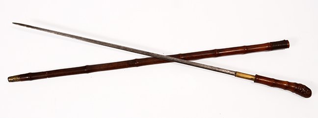 69. Japanese Sword Cane- Ca. 1900- A dark brown bamboo: 69. Japanese Sword Cane- Ca. 1900- A dark brown bamboo root handle and shaft, woven leather collar, metal ferrule, 25 ¼” inch two-sided blade with push/pull mechanism. H.- 6” x 1 ½” O.L.- 37��