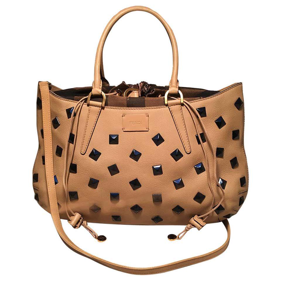 FENDI Tan Calfskin Leather Navy Studded Medium B. Fab: FENDI Tan Calfskin Leather Navy Studded Medium B. Fab Tote Bag. Tan soft leather exterior trimmed with navy blue studs throughout, matte gold hardware, and signature brown zucca stripped canvas drawst
