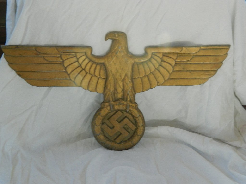 WWII SS Eagle NSDAP Metal Wall Plaque/Railroad Eagle: Gold painted metal SS mobile Eagle facing left. Has wreath with swastika in talons. This is either a railroad or building plaque.Measures 22.5" in width and 14" in height.