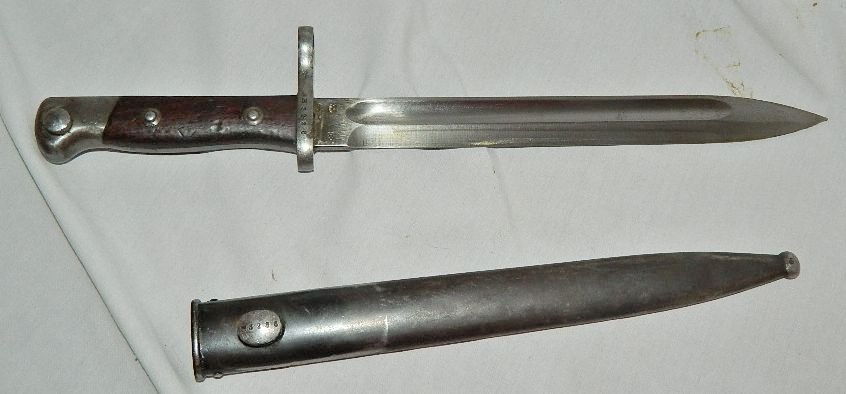 Antique Weyersberg Kirschbaum Mauser Bayonet B3286: This bayonet bears the Weyersburg Kirschbaum & Co logo. The fittings on this piece are metal alloy. There are scratches, scuffs and some light rust/pit spots in some areas.The grips are made from wood