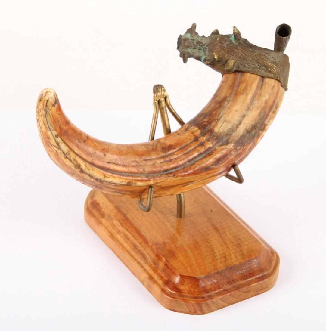 WARTHOG TUSK WITH DECORATIVE BRASS FIXTURE: WARTHOG TUSK WITH DECORATIVE BRASS FIXTURE Warthog tusk with decorative brass fixture accented with carnelian. Includes wooden base. Shipping / Pickup: We Can Ship This Item