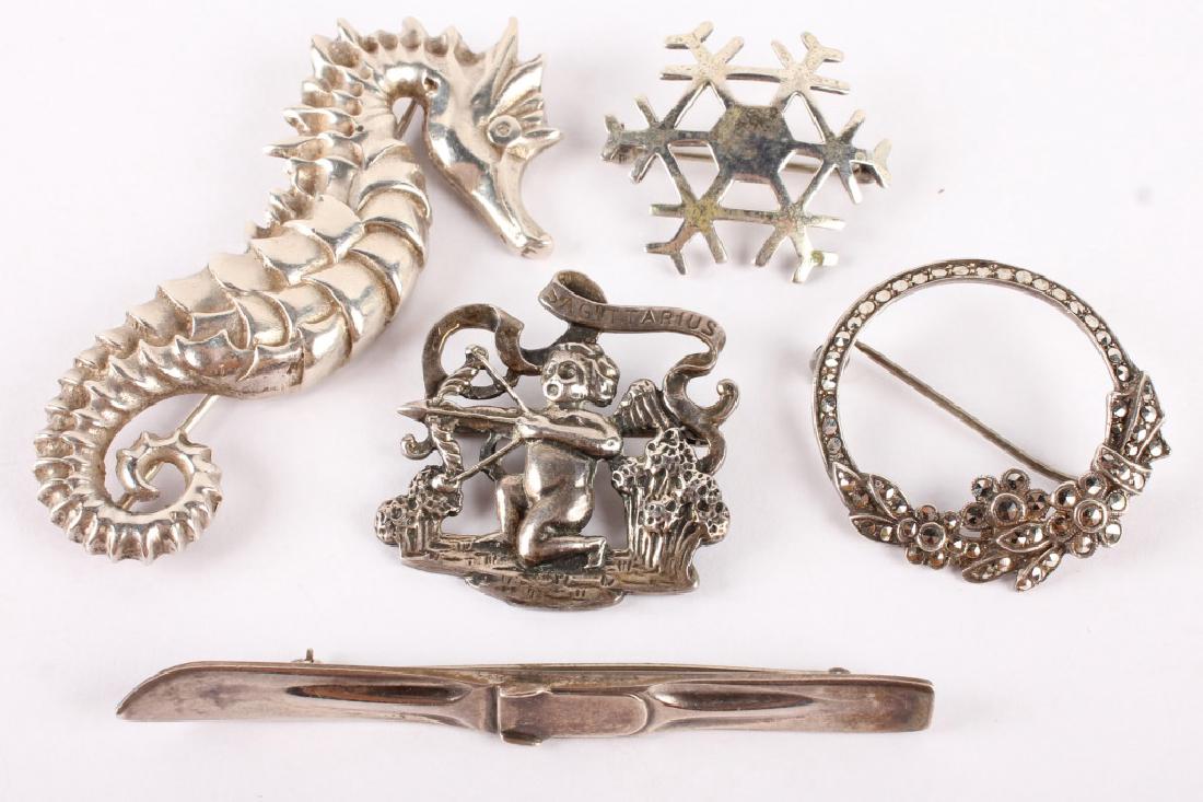 5 STERLING SILVER BROOCHES: 5 STERLING SILVER BROOCHES Lot of 5 sterling silver brooches, one snowflake, one cherub, one seahorse, one ski, and one marcasite. Weight: 47.2 grams total Size: 1.25 to 3" Shipping / Pickup: We Can S