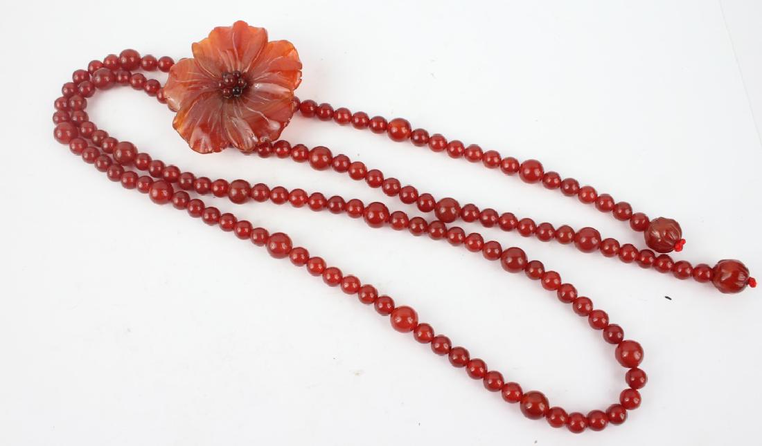 CHINESE CARVED CARNELIAN BROOCH & NECKLACE: CHINESE CARVED CARNELIAN BROOCH & NECKLACE Carved carnelian floral blossom brooch / pendant with a beaded carnelian necklace. Weight: 79.4 grams Size: 36" necklace, 1.75" brooch Shipping / Pickup: We 
