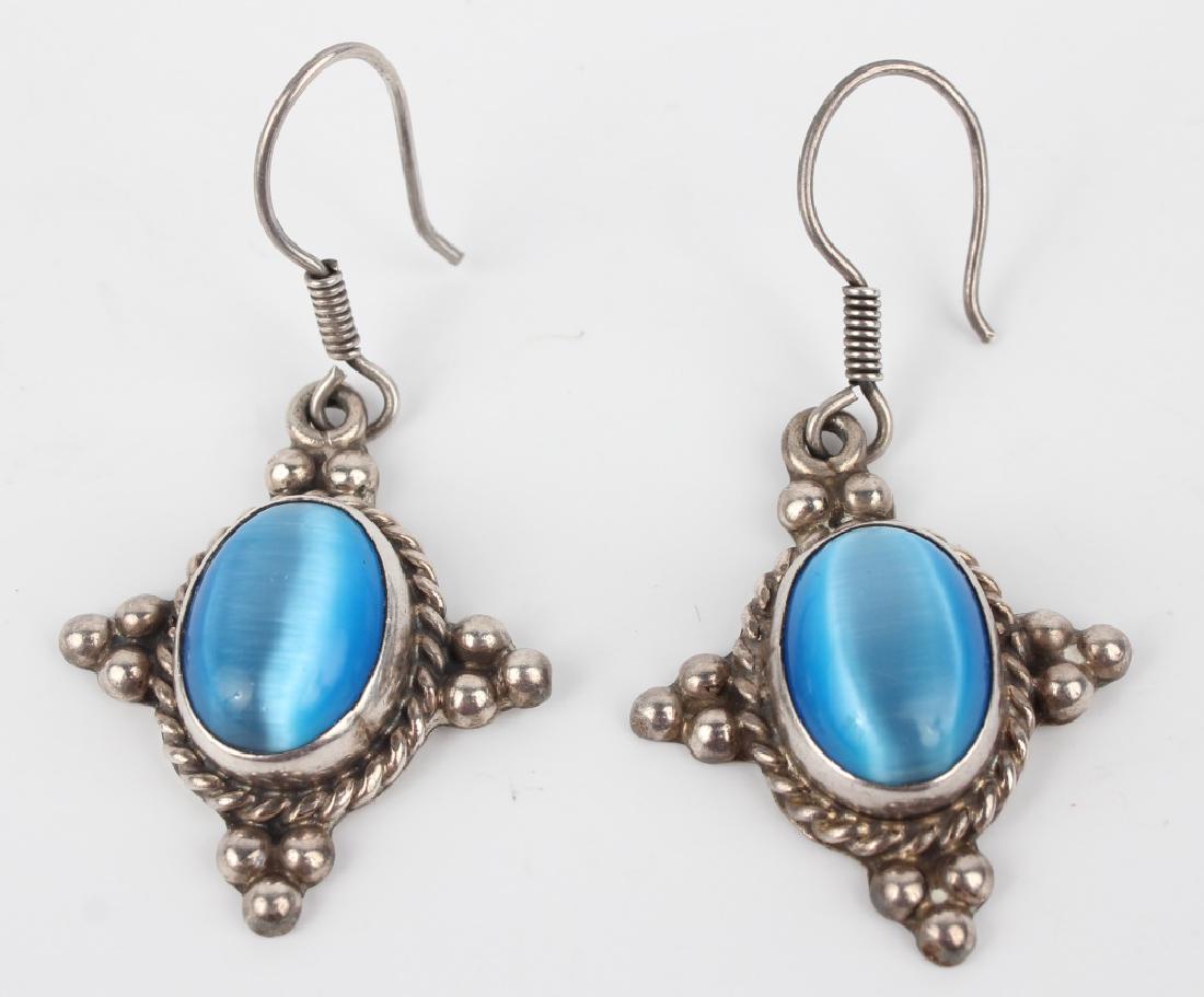 STERLING SILVER SYNTHETIC CAT'S EYE EARRINGS: STERLING SILVER SYNTHETIC CAT'S EYE EARRINGS Sterling silver fish hook earrings with synthetic blue cat's eye stones ornately accented by rope pattern. 1 1/4 inch long x 1 inch wide. Weight: 12.6g Shi