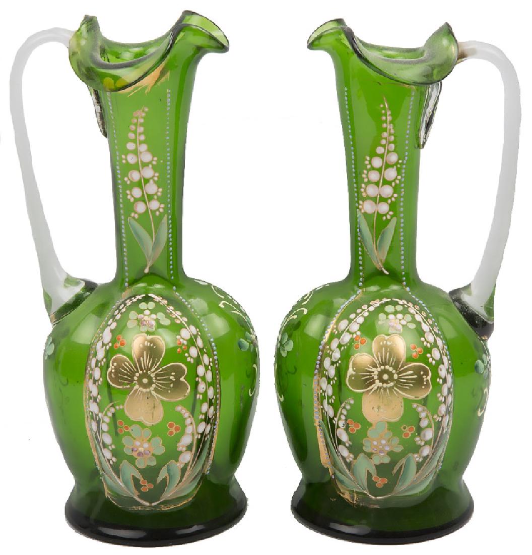 PAIR OF PAINTED GREEN GLASS FLORAL MOTIF EWERS: PAIR OF PAINTED GREEN GLASS FLORAL MOTIF EWERS Lot of two green blown art glass pitchers, each with hand painted floral accents and ruffled rims. Size: 9 x 3.75 x 3.75" Shipping / Pickup: We Can Ship