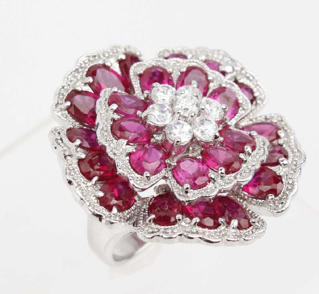 STERLING SILVER RING WITH ENHANCED RUBYS: STERLING SILVER RING WITH ENHANCED RUBYS Sterling silver flower ring with enhanced oval rubies and cubic zirconia. Weight: 19.1 g
