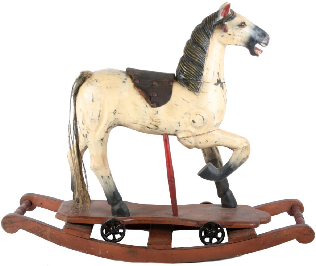 20TH CENTURY PAINTED WOOD ROCKING HORSE: 20TH CENTURY PAINTED WOOD ROCKING HORSE Wood carved and painted rocking horse with cast iron wheels and leather saddle. Size: 27" tall, 33" long