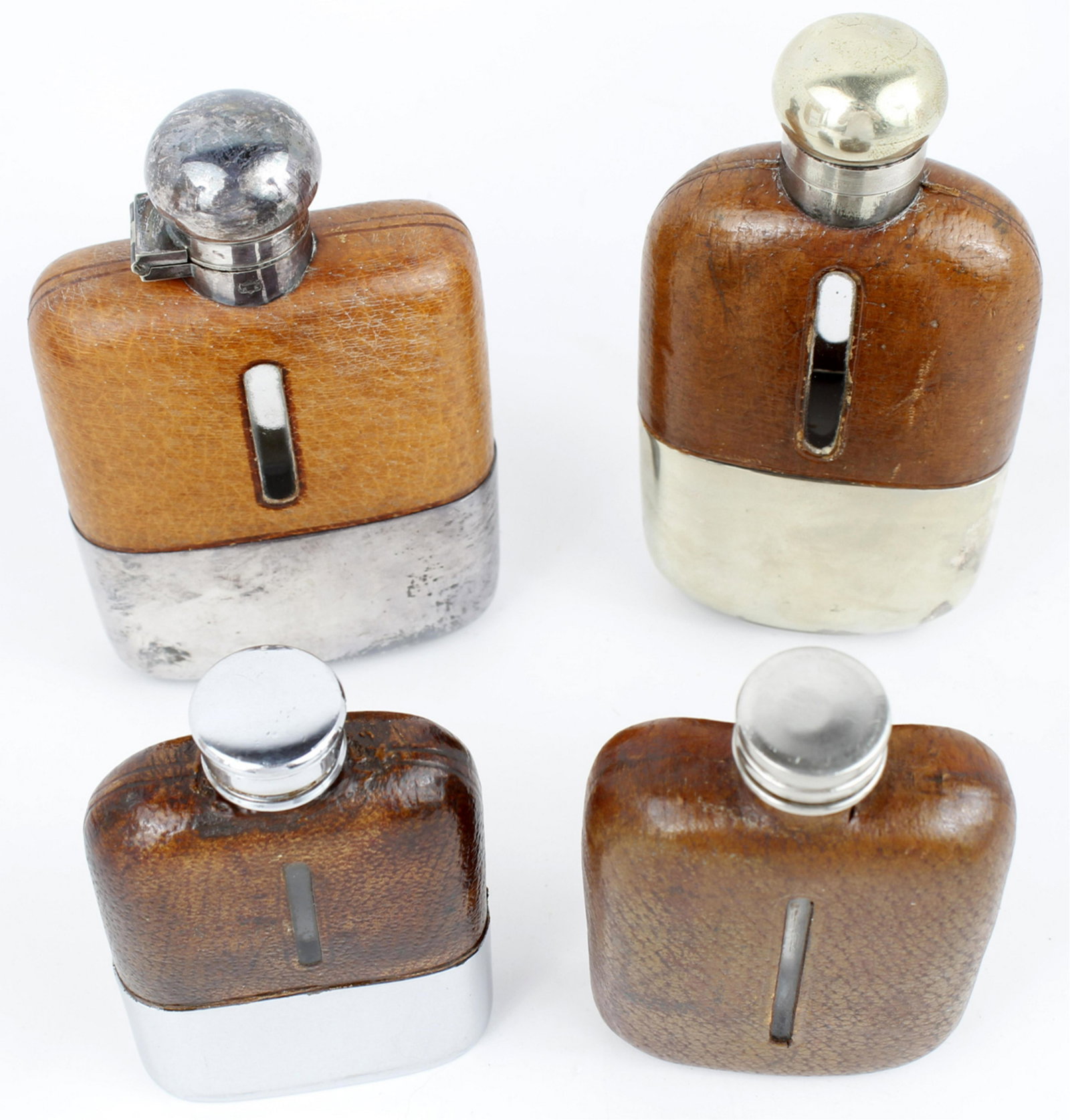 ENGLISH LEATHER & SILVER HIP FLASKS - LOT OF 4: ENGLISH LEATHER & SILVER HIP FLASKS - LOT OF 4 To include: A late 19th Century small leather, glass and silver plate (lid) hip flask, the leather cut away to indicate liquid levels. Very good conditio