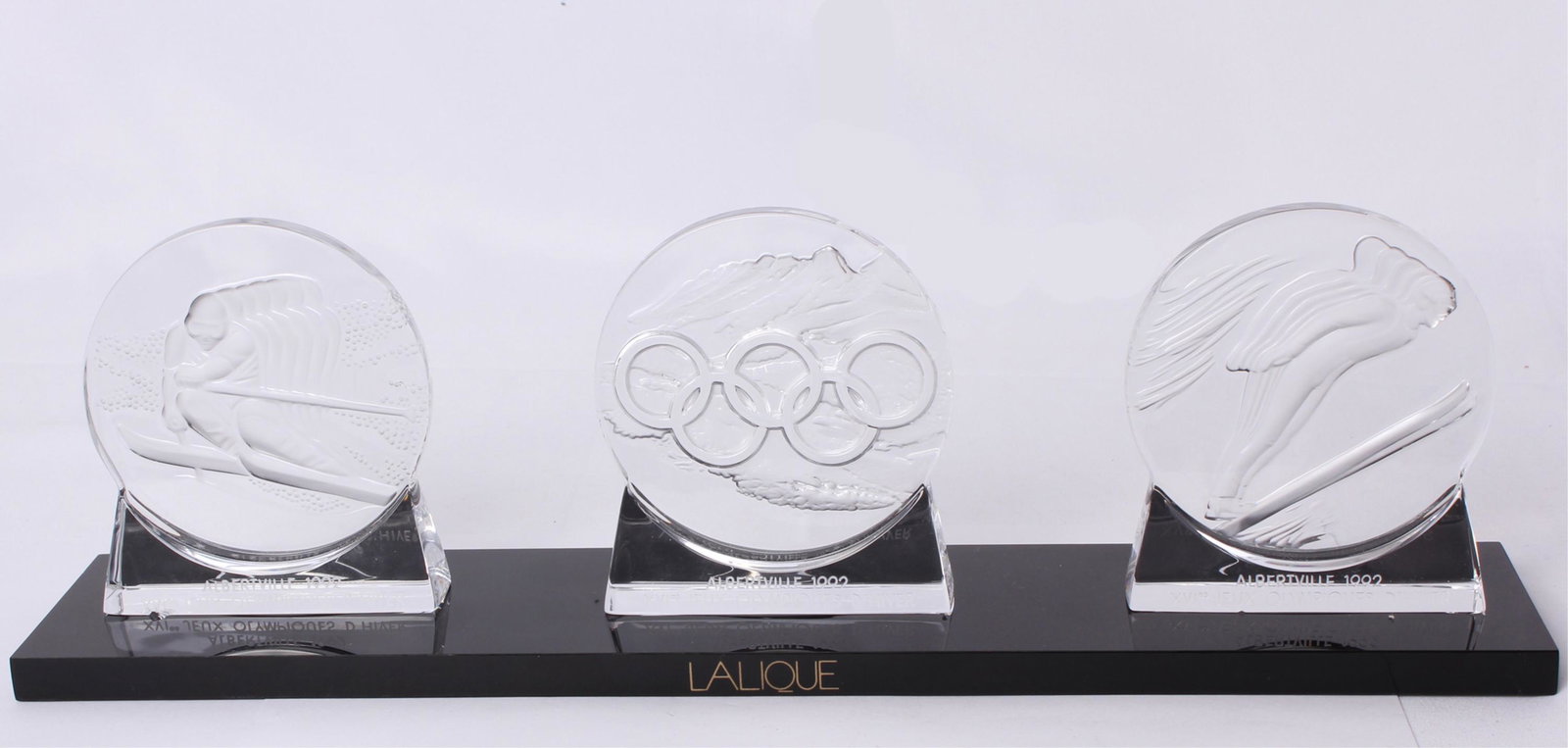 LALIQUE WINTER OLYMPICS XVI MEDALLIONS ALBERTVILLE: LALIQUE WINTER OLYMPICS XVI MEDALLIONS ALBERTVILLE Lalique crystal limited edition winter Olympics XVI Alberta 1992 medallions on black Lucite Lalique stand. Includes Downhill skiing 1800/4000, Olympi