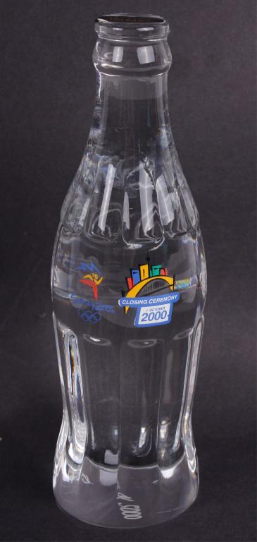 OLYMPIC SYDNEY 2000 COCA COLA BOTTLE AND C.O.A.: OLYMPIC SYDNEY 2000 COCA COLA BOTTLE AND C.O.A. 24% solid lead glass Coca Cola bottle from the Sydney 2000 Olympics. Includes certificate of authenticity. Limited edition #472/2000.Size: 7.75 X 2.25" 