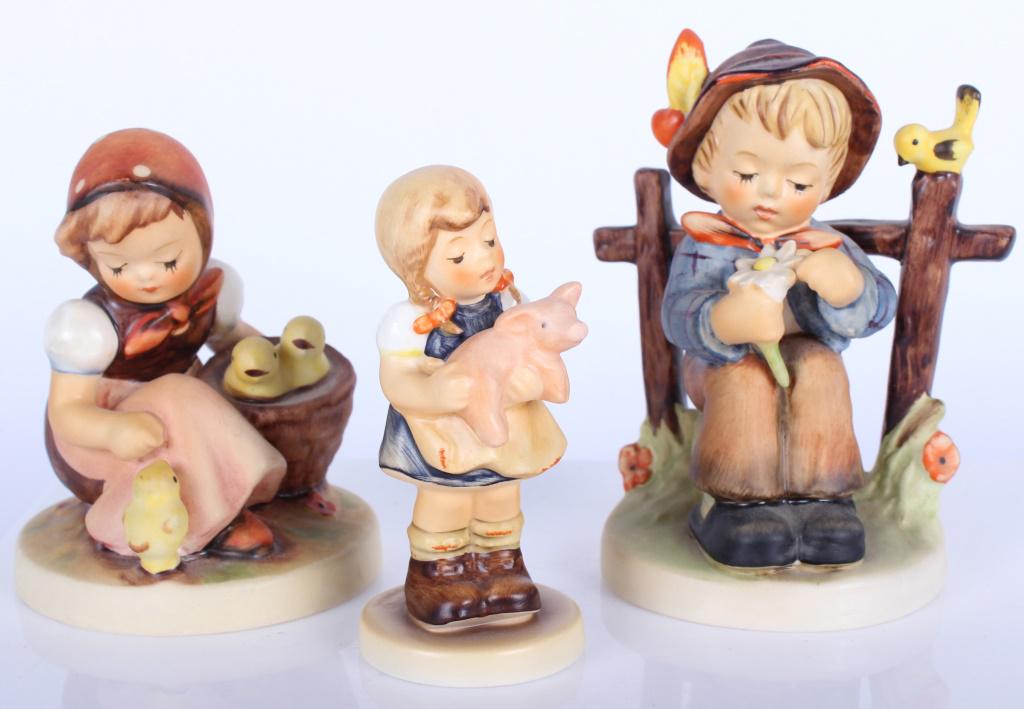 MJ HUMMEL GOEBEL VINTAGE FIGURINES - LOT OF 3: 10324MJ HUMMEL GOEBEL VINTAGE FIGURINES - LOT OF 3 MJ Hummel Goebel porcelain figurines. Lot to include one boy figurine sitting on a well with a bird sitting behind him from 1955, one girl figurine h