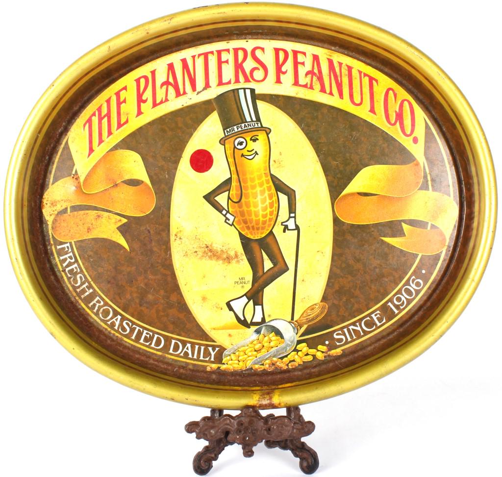 VINTAGE PLANTERS PEANUT CO. SERVING PLATE & STAND: 10341VINTAGE PLANTERS PEANUT CO. SERVING PLATE & STAND Vintage Planters Peanut Co. metal serving plate, depicting their logo and states "Fresh roasted daily since 1906." Plate comes with metal stand.S