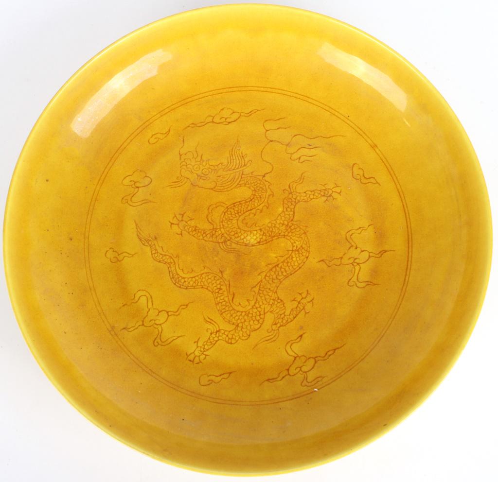 CHINESE PORCELAIN DRAGON PLATE WI/ YELLOW GLAZE: 10814CHINESE PORCELAIN DRAGON PLATE WI/ YELLOW GLAZE Chinese porcelain dragon plate with ocher yellow glaze and six-character bottom mark. Size: 8.75" Length Condition: Very fine. 8.75" Length