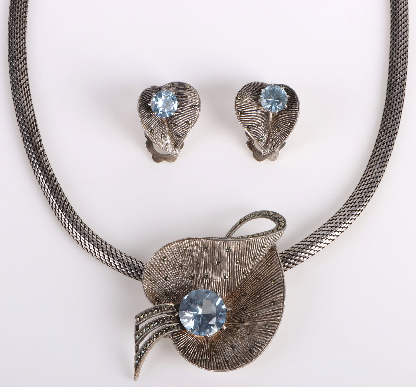 STERLING SILVER TOPAZ LEAF NECKLACE & EARRINGS: 179031 STERLING SILVER TOPAZ LEAF NECKLACE & EARRINGS Sterling silver blue topaz leaf necklace and earrings with one 5.0ct blue topaz and two 1.0ct blue topaz. Stone Type: Topaz Weight: 38.0 Grams Siz