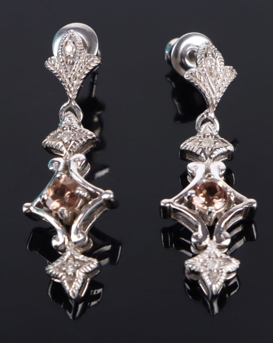 0.63CTW GARNET 14K WHITE GOLD DIAM. EARRINGS: 181141 0.63CTW GARNET 14K WHITE GOLD DIAM. EARRINGS 0.63ctw color change garnet 14k white gold diamond earrings with four 0.04ctw round diamonds and two 0.015ctw round diamonds. Earrings come with cer
