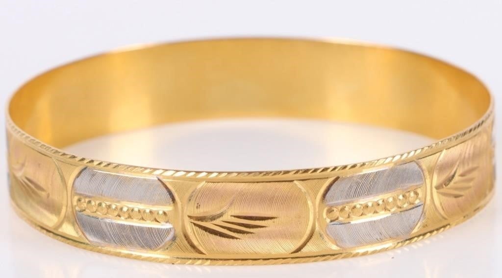 23K YELLOW GOLD ALTERNATING ENGRAVED LADIES BANGLE: 23K yellow gold alternating engraved ladies bangle to include a beautiful alternating white and yellow alternating engraved design. Weight: 22.93 Grams Size: 2.50" Condition: Very fine.