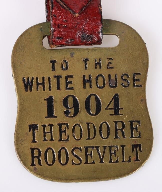 1904 T. ROOSEVELT TO THE WHITEHOUSE WATCH FOB: 1904 Theodore Roosevelt To The Whitehouse brass presidential campaign watch fob w/ original strap still attached. Size: 5.50" Condition: Wear commensurate with age.