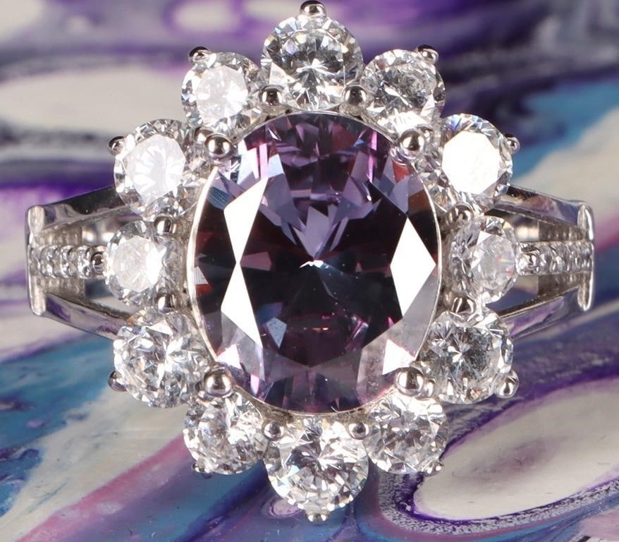 STERLING SILVER LADIES RING W/ BICOLOR SAPPHIRE: Sterling silver ladies ring with a 2.5ct oval diamond-cut bicolor sapphire center gemstone surrounded by glittering cubic zirconium stones about the face and on the shoulders.Stone Type: SapphireSize: