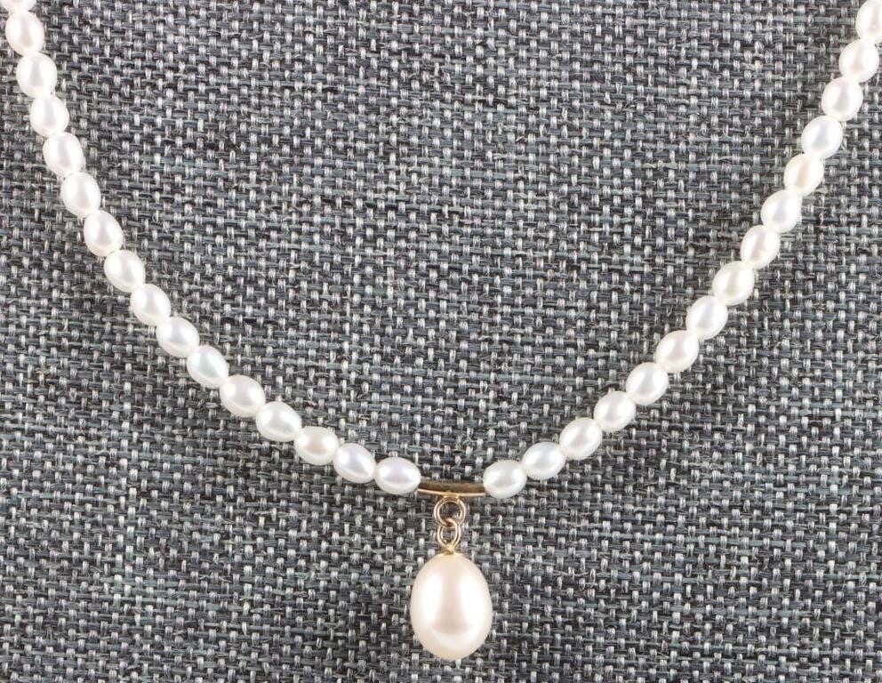 ELEGANT 14K YELLOW GOLD LADIES PEARL NECKLACE: 14K yellow gold ladies pearl necklace. The pearls lining the band are freshwater while the pendant is a 9.5 mm tall egg-shaped pearl. The gold is located on the clasp, above the pendant, and as beads