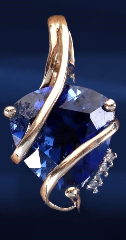 10KT YELLOW GOLD LADIES PENDANT W/ SAPPHIRE & DIAS: 10kt yellow gold ladies pendant with a 5ct trillion-cut blue sapphire center gemstone and four melee diamonds set on one side of it. A ribbon of gold twists over the sapphire, subtly concealing yet al