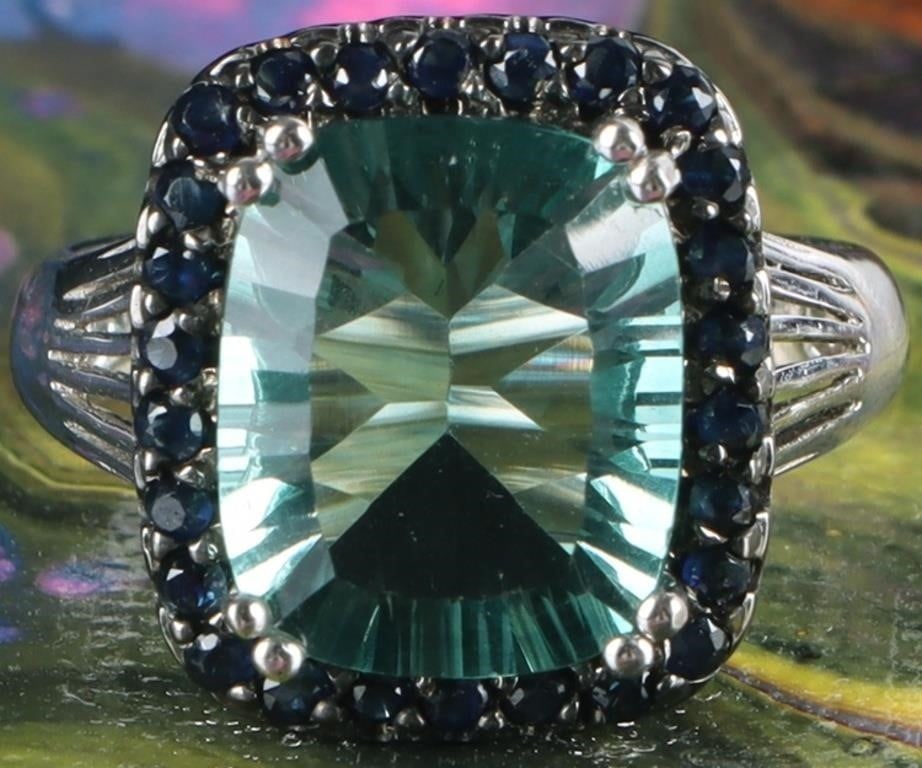 2CT CUSHION CUT AQUAMARINE & SAPPHIRE LADIES RING: 2CT cushion cut aquamarine & sapphire ladies halo ring. The center stone is a 2CT aquamarine surrounded by a halo of sapphires set in sterling silver.Stone Type: AquamarineWeight: 4.48 GramsSize: US