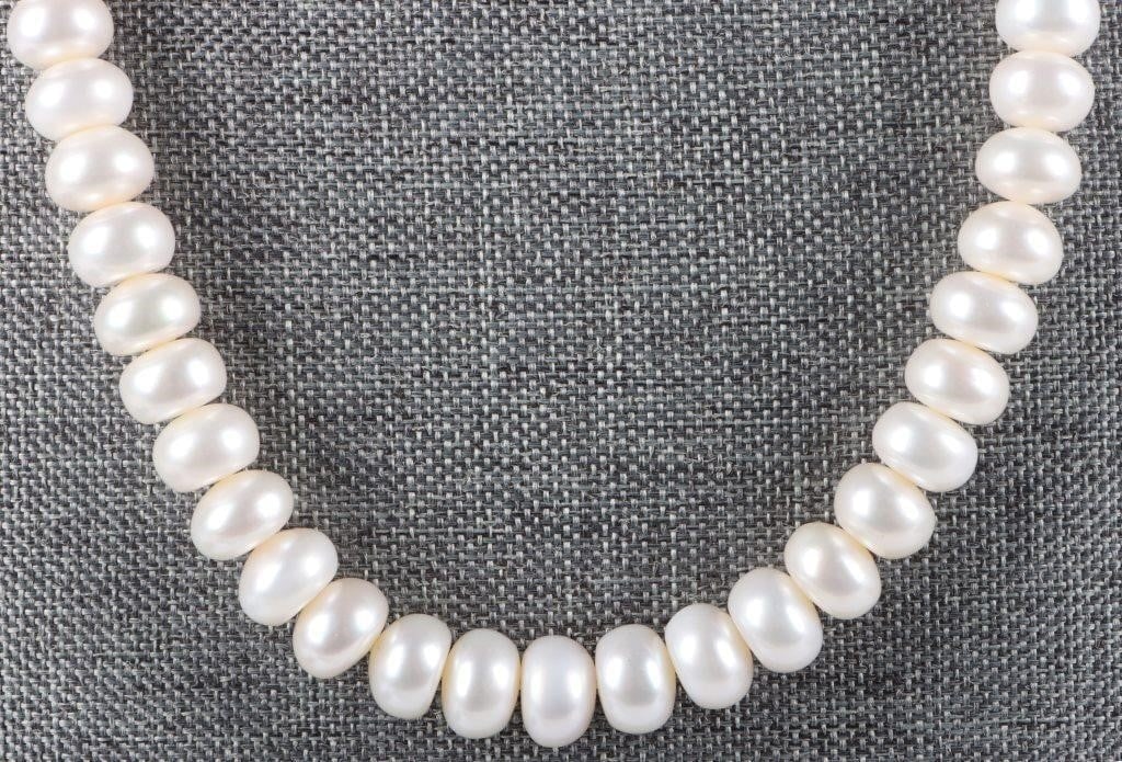 64-BAROQUE GENUINE PEARL LADIES NECKLACE: Ladies necklace with sixty-four Baroque genuine pearls. Each is shaped like a flat cylinder. The clasp of this piece is silver-toned and designed like a conical spring.Stone Type: PearlSize: 19.5" lon