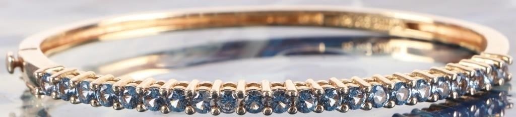 GOLD TONED BLUE TOPAZ LADIES BANGLE BRACELET: Gold tone sterling silver blue topaz ladies bangle bracelet. There are twenty-two 0.07CT round topaz across the top of the bracelet.Stone Type: TopazWeight: 11.15 GramsSize: See descriptionCondition: