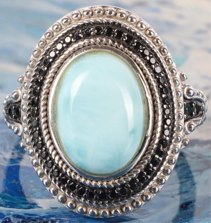 STERLING SILVER BLUE LARIMAR ONYX LADIES RING: Sterling silver blue larimar onyx ladies ring. Gemstones to include one 14.30 mm X 10.08 mm blue larimar, and fifty 0.01ct round cut onyx. Stone Type: Assorted Weight: 8.32 Grams Size: 10.00 U.S. Cond