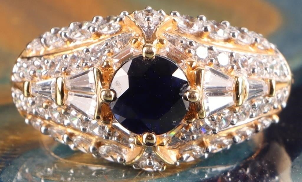 GOLD-TONE STERLING SILVER LADIES RING W/ SAPPHIRE: Gold-tone sterling silver ladies ring with a 0.75ct round-cut blue sapphire gemstone surrounded by brilliant white rhinestones. Stone Type: Sapphire Weight: 4.45 grams Size: US 7.25 Condition: See pic