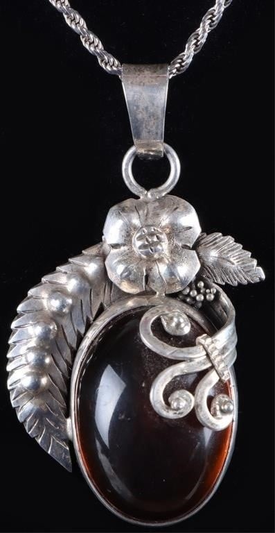 STERLING SILVER LADIES NECKLACE W/ AMBER STONE: Sterling silver ladies necklace with a large polished amber stone. The stone is surrounded by floral and vegetative designs. Stone Type: Amber Weight: 19.2 grams Size: 18" long Condition: See pictures