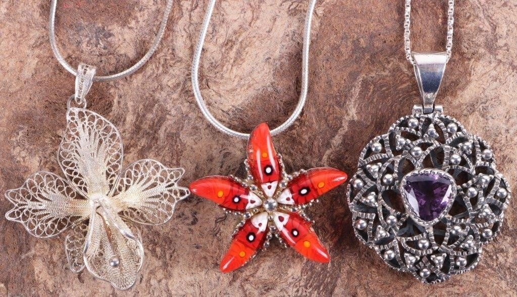 STYLISH STERLING SILVER LADIES NECKLACES FILIGRE-3: Lot of three stylish sterling silver ladies necklaces, to include one with a filigree lily pendant, one with a pendant featuring a trillion-cut amethyst center stone surrounded by a radiating pattern 