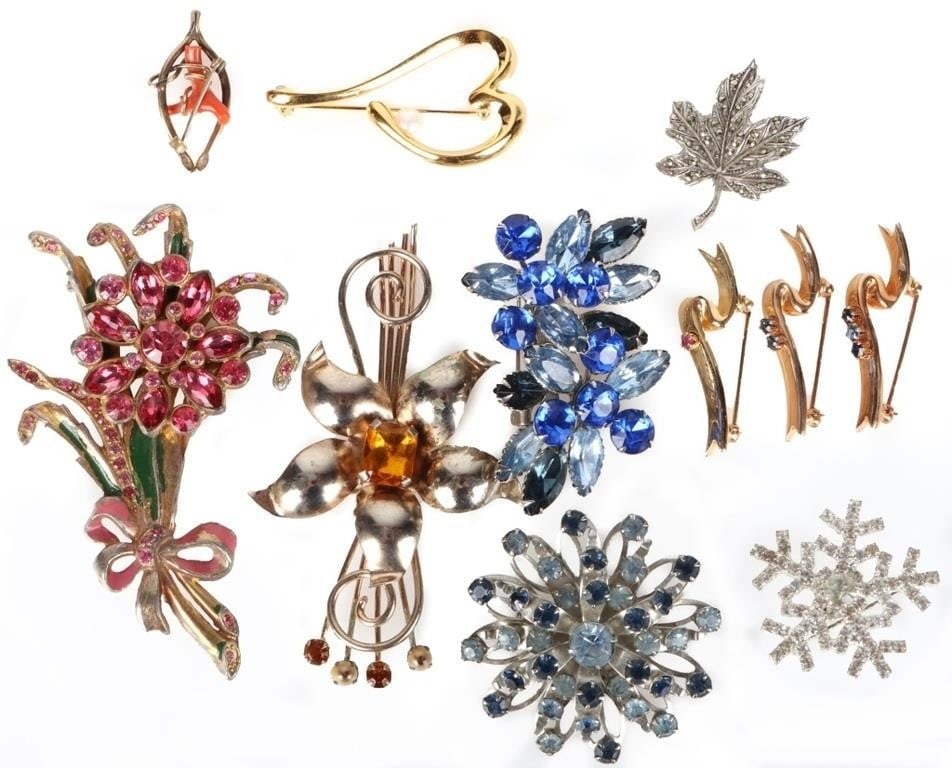 ASSORTED LADIES BROOCHES PINK TOPAZ SAPPHIRE (11): Ladies assorted brooches lot of 11. Of note are a leaf brooch studded with spinel, a brooch with two .06CT topaz gemstones flanking a pale blue sapphire gemstone, a brooch with a .06CT pink sapphire g