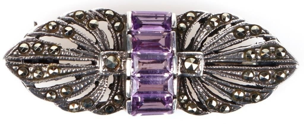 STERLING SILVER LADIES BROOCH AMETHYST GEMSTONE: Sterling silver ladies brooch with five amethyst center gemstones with grey spinel surrounding. Stone Type: Amethyst Weight: 5.36 grams Size: 1.5" Condition: Very fine.