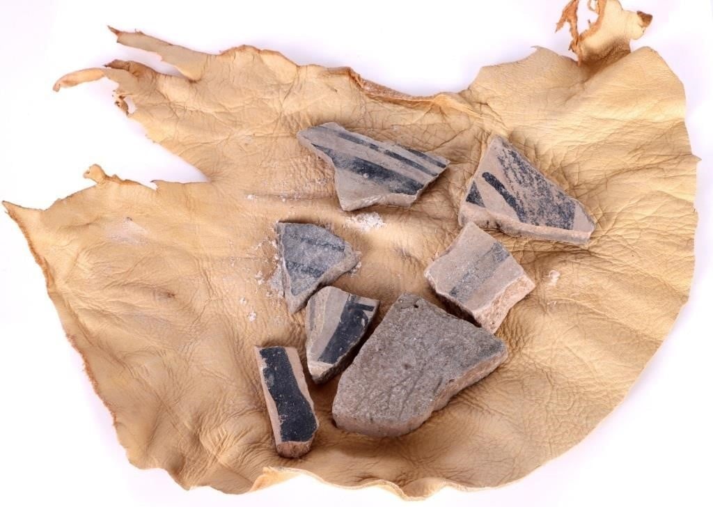 NATIVE AMERICAN COLLECTIBLE POTTERY SHARDS - (7): Native American collectible pottery shards wrapped in cut leather. Seven shards total, all shards appear to originate from the same work. Size: 2.0" Largest Condition: Wear commensurate with age.